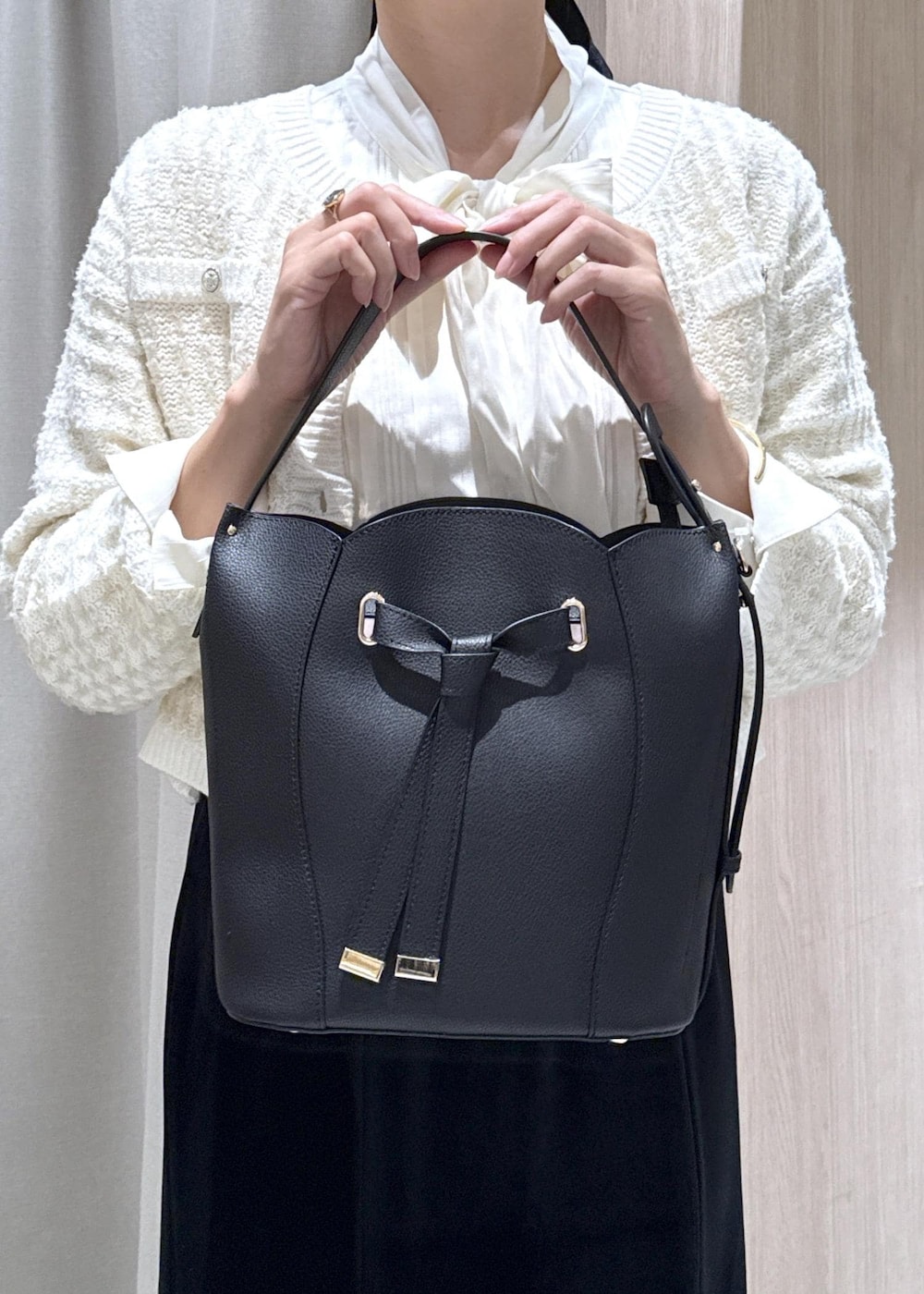 ブラック系のパンプス、ホワイト系のカーディガン/ボレロ、ブラック系のショルダーバッグを着用したレディースの秋コーディネートの6枚目の写真