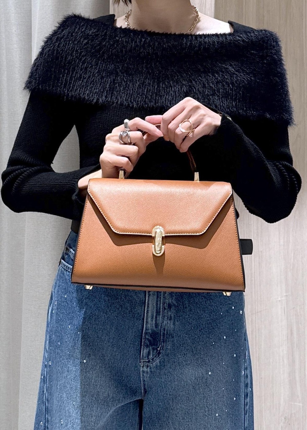 ブルー系のデニムパンツ、イエロー系のハンドバッグ、ブラック系のニット/セーターを着用したレディースの冬コーディネートの9枚目の写真