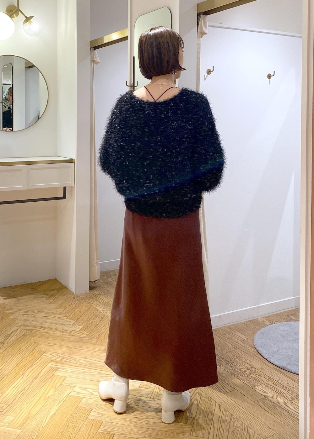 ホワイト系のブーツ、ブラック系のハンドバッグ、ブラック系のニット/セーターを着用したレディースの冬コーディネートの3枚目の写真