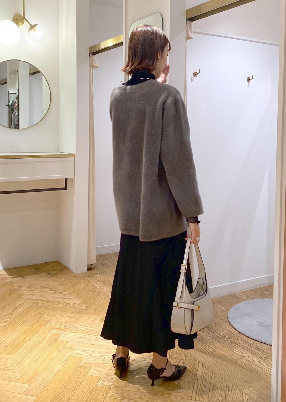 ブラック系のパンプス、ブラック系のスカート、ブラウン系のその他アウターを着用したレディースの秋コーディネートの3枚目の写真