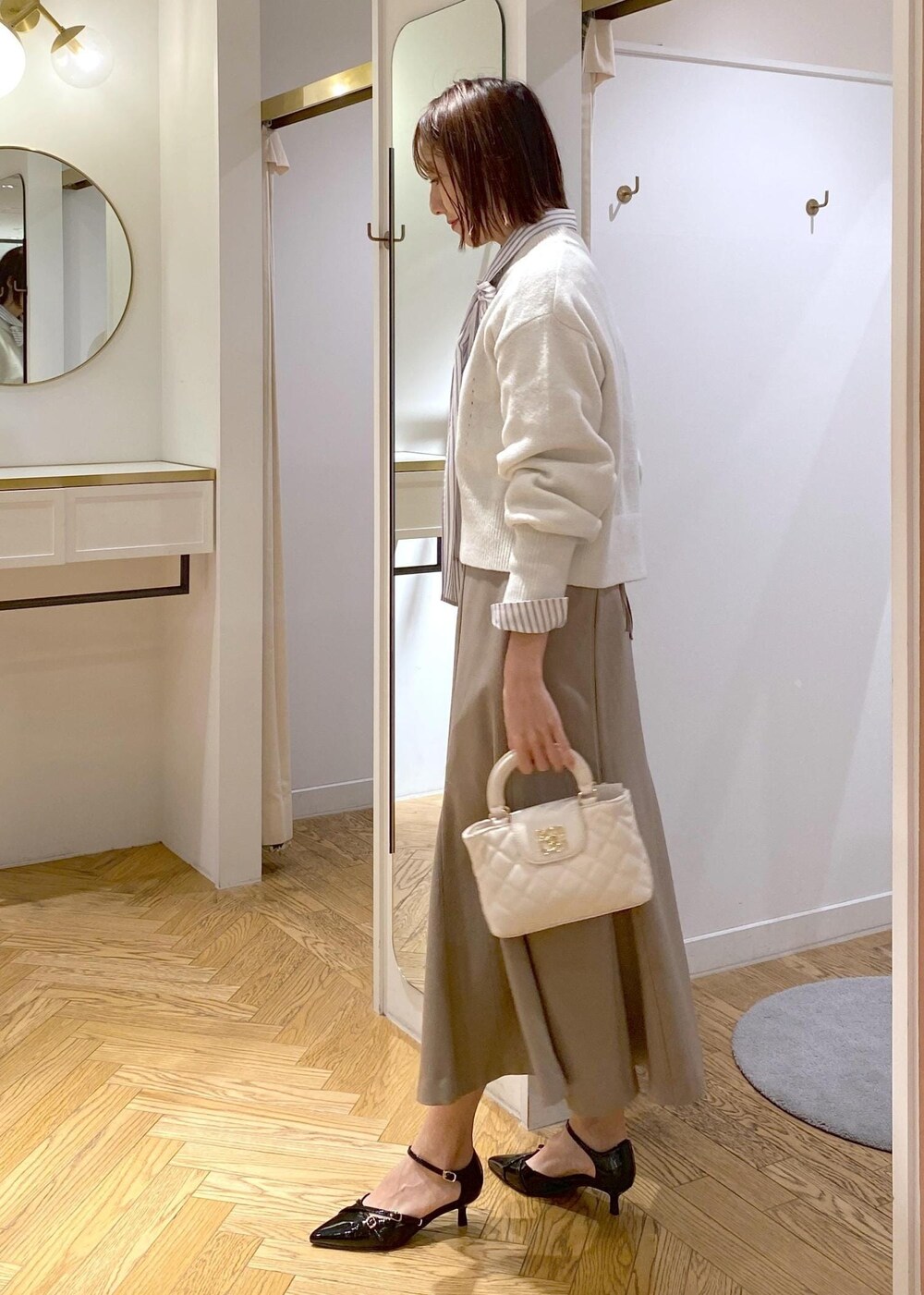 ブラック系のパンプス、ベージュ系のスカート、ホワイト系のシャツ/ブラウスを着用したレディースの冬コーディネートの2枚目の写真