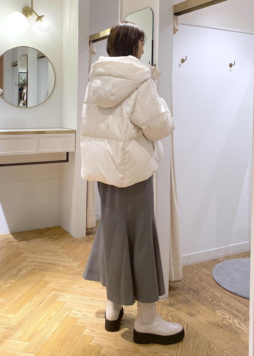ホワイト系のブーツ、グレー系のスカート、ホワイト系のダウンジャケット/コートを着用したレディースの冬コーディネートの3枚目の写真