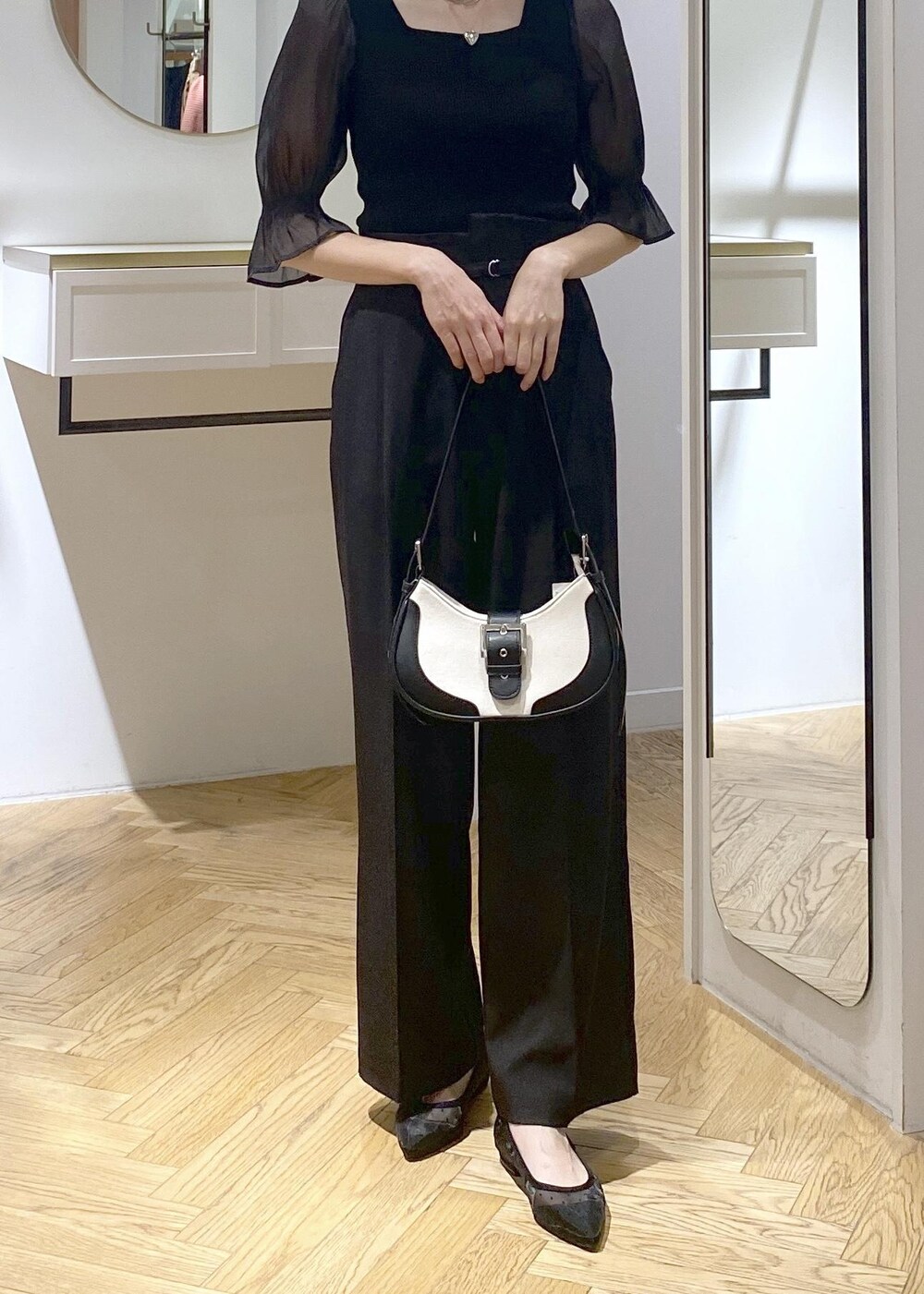 ブラック系のパンプス、ブラック系のショルダーバッグ、ブラック系のスラックスを着用したレディースの夏コーディネートの2枚目の写真