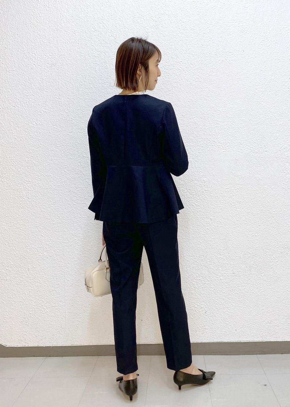 ブラック系のパンプス、ホワイト系のシャツ/ブラウス、ブルー系のスラックスを着用したレディースの冬コーディネートの2枚目の写真