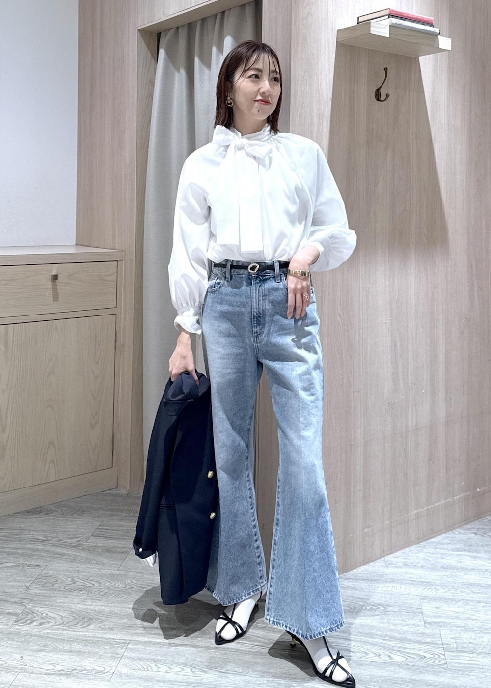 ブルー系のテーラードジャケット、ブラック系のショルダーバッグ、ブルー系のデニムパンツを着用したレディースの冬コーディネートの6枚目の写真