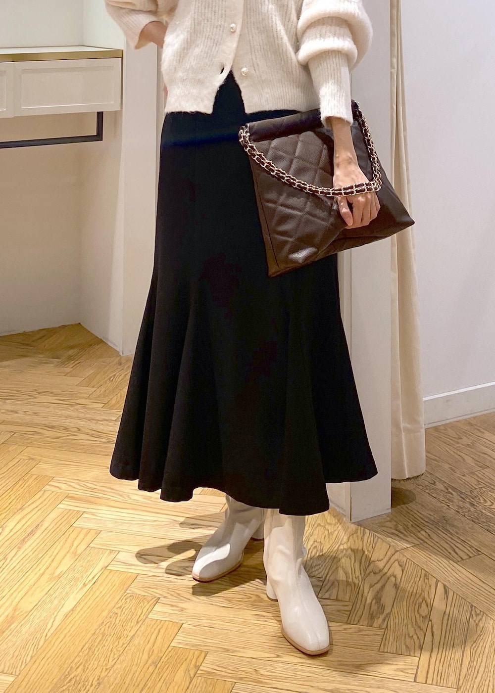 ホワイト系のブーツ、ブラック系のスカート、ブラウン系のショルダーバッグを着用したレディースの秋コーディネートの5枚目の写真