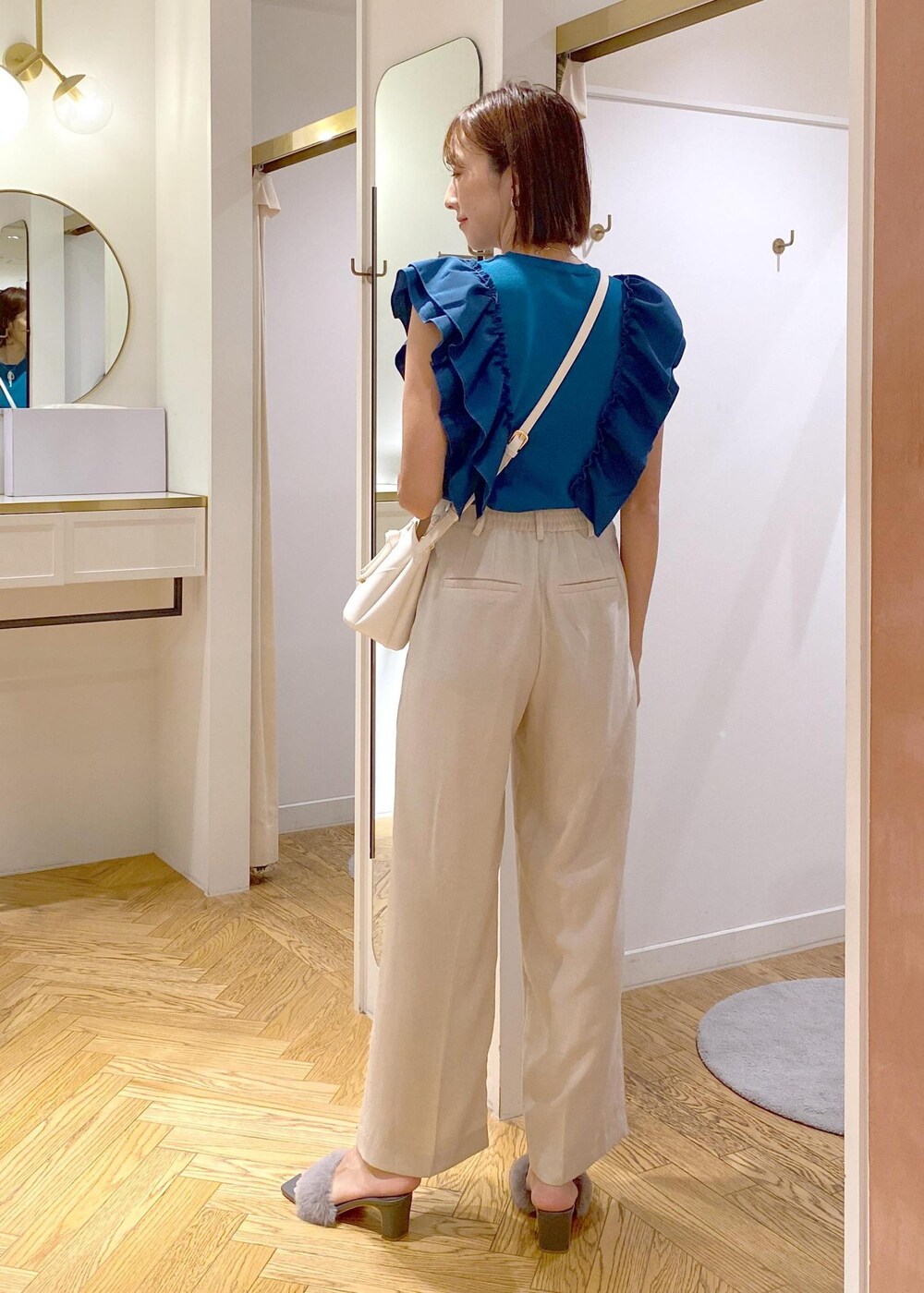 ホワイト系のスラックス、ホワイト系のショルダーバッグ、グレー系のドレスシューズを着用したレディースの夏コーディネートの6枚目の写真