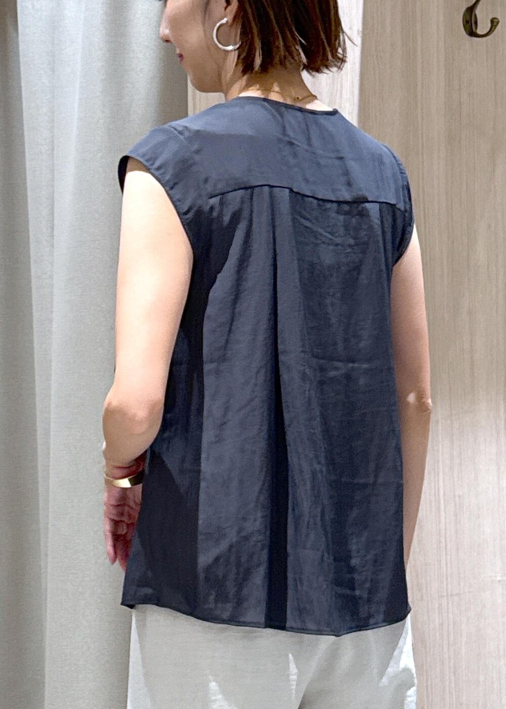 ブラック系のハンドバッグ、ブラック系のパンプス、ホワイト系のスラックスを着用したレディースの夏コーディネートの10枚目の写真