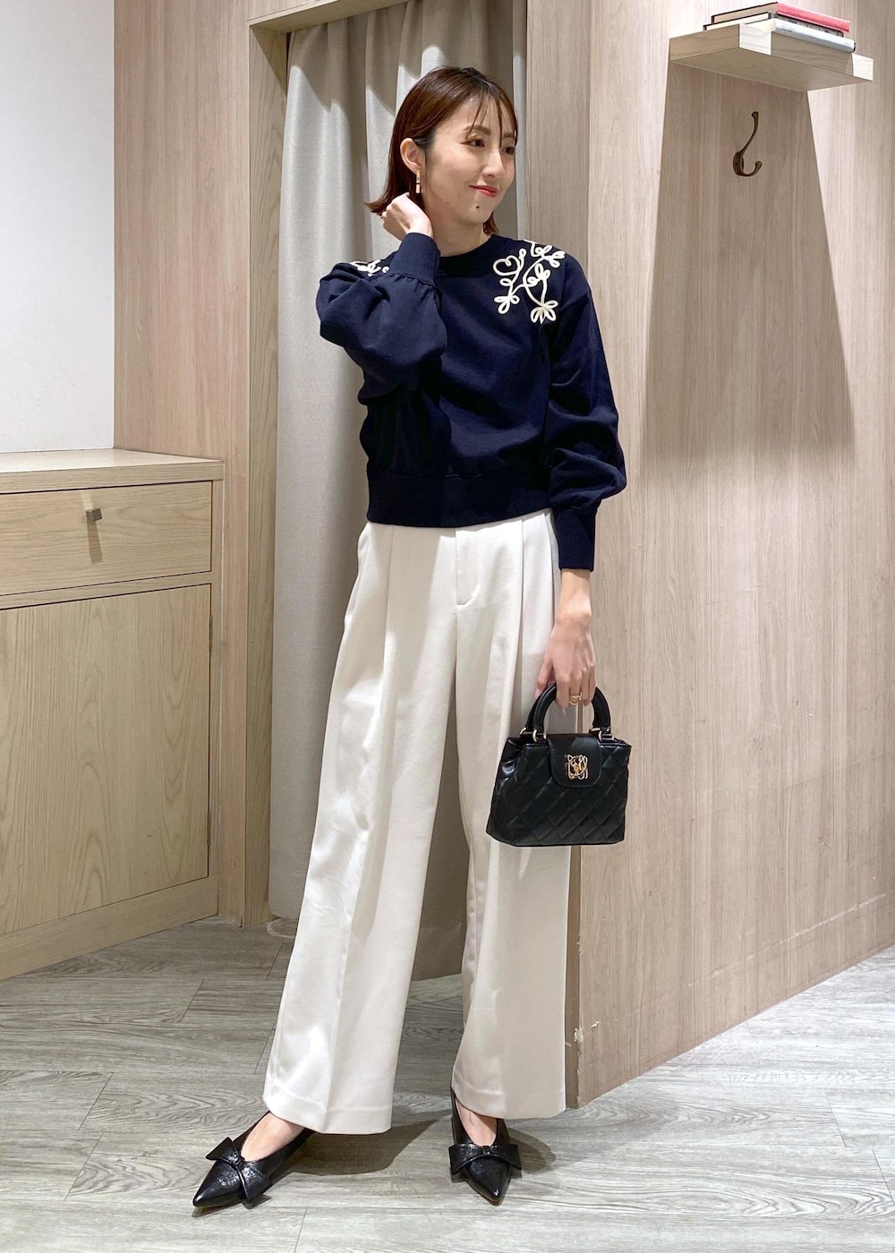 ブラック系のパンプス、ブルー系のニット/セーター、ホワイト系のスラックスを着用したレディースの冬コーディネートの5枚目の写真