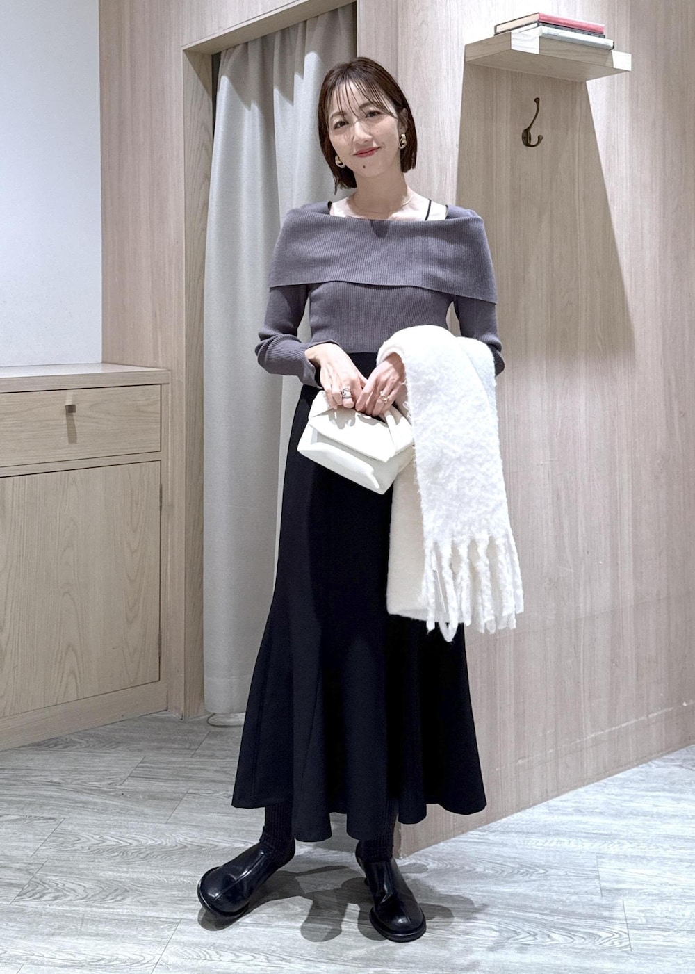 ブラック系のスカート、グレー系のニット/セーター、ホワイト系のショルダーバッグを着用したレディースの冬コーディネートの2枚目の写真