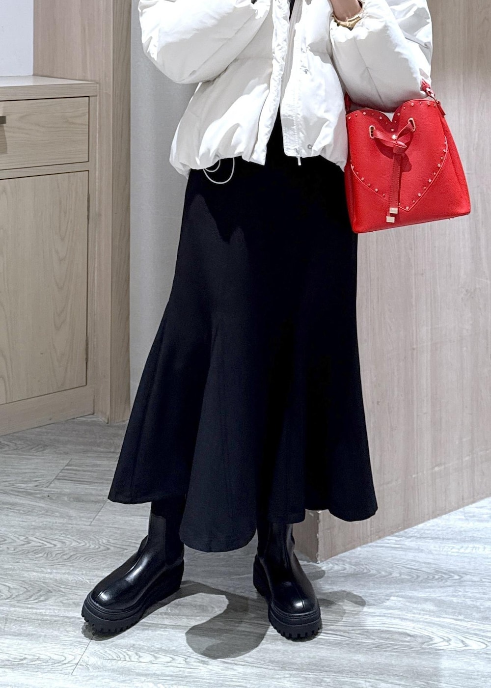 ブラック系のスカート、ブラック系のブーツ、グレー系のニット/セーターを着用したレディースの冬コーディネートの2枚目の写真