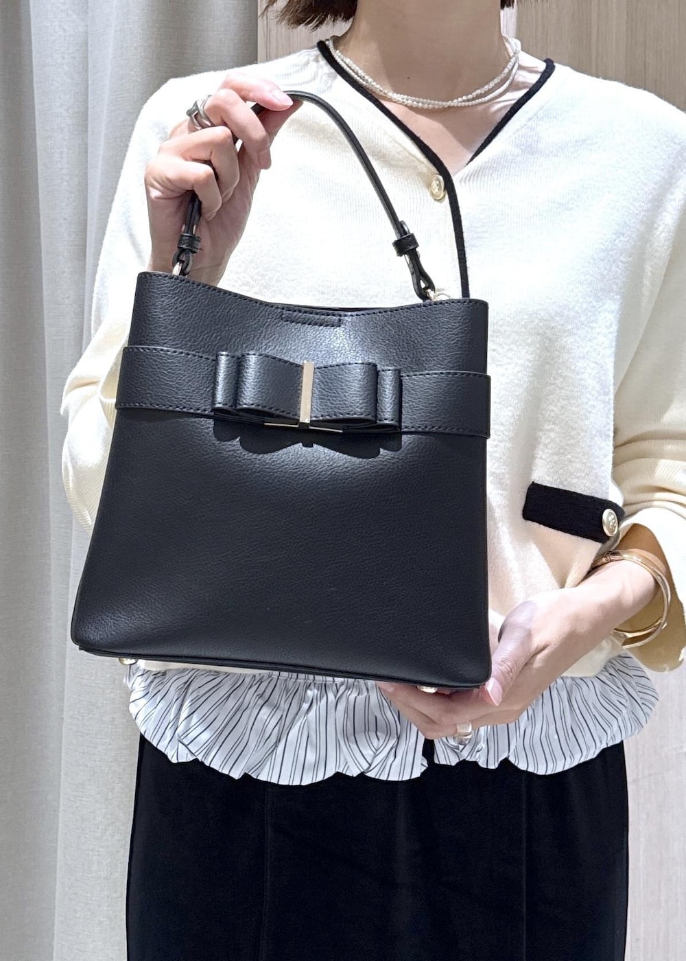 ブラック系のパンプス、ブラック系のショルダーバッグ、ブラック系のスカートを着用したレディースの秋コーディネートの7枚目の写真