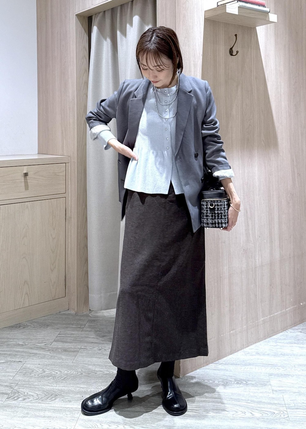 グレー系のテーラードジャケット、ブルー系のカーディガン/ボレロ、ブラウン系のスカートを着用したレディースの秋コーディネートの4枚目の写真