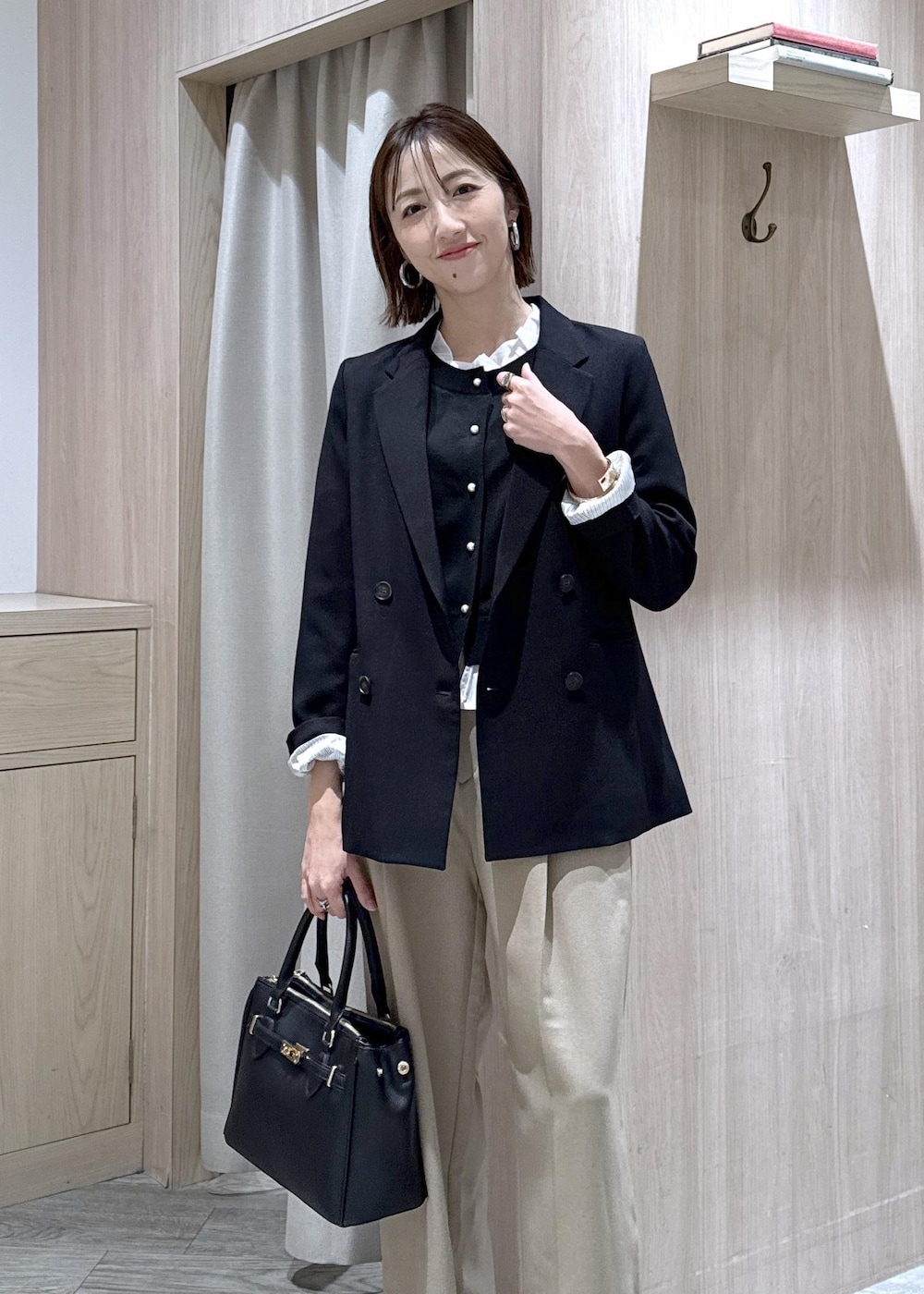 ブラック系のショルダーバッグ、ベージュ系のスラックス、ブラック系のテーラードジャケットを着用したレディースの冬コーディネートの10枚目の写真