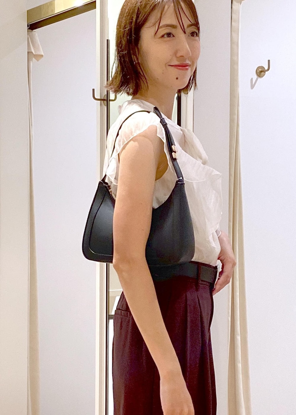 ブラック系のハンドバッグ、ブラック系のパンプス、ブラウン系のスラックスを着用したレディースの夏コーディネートの6枚目の写真