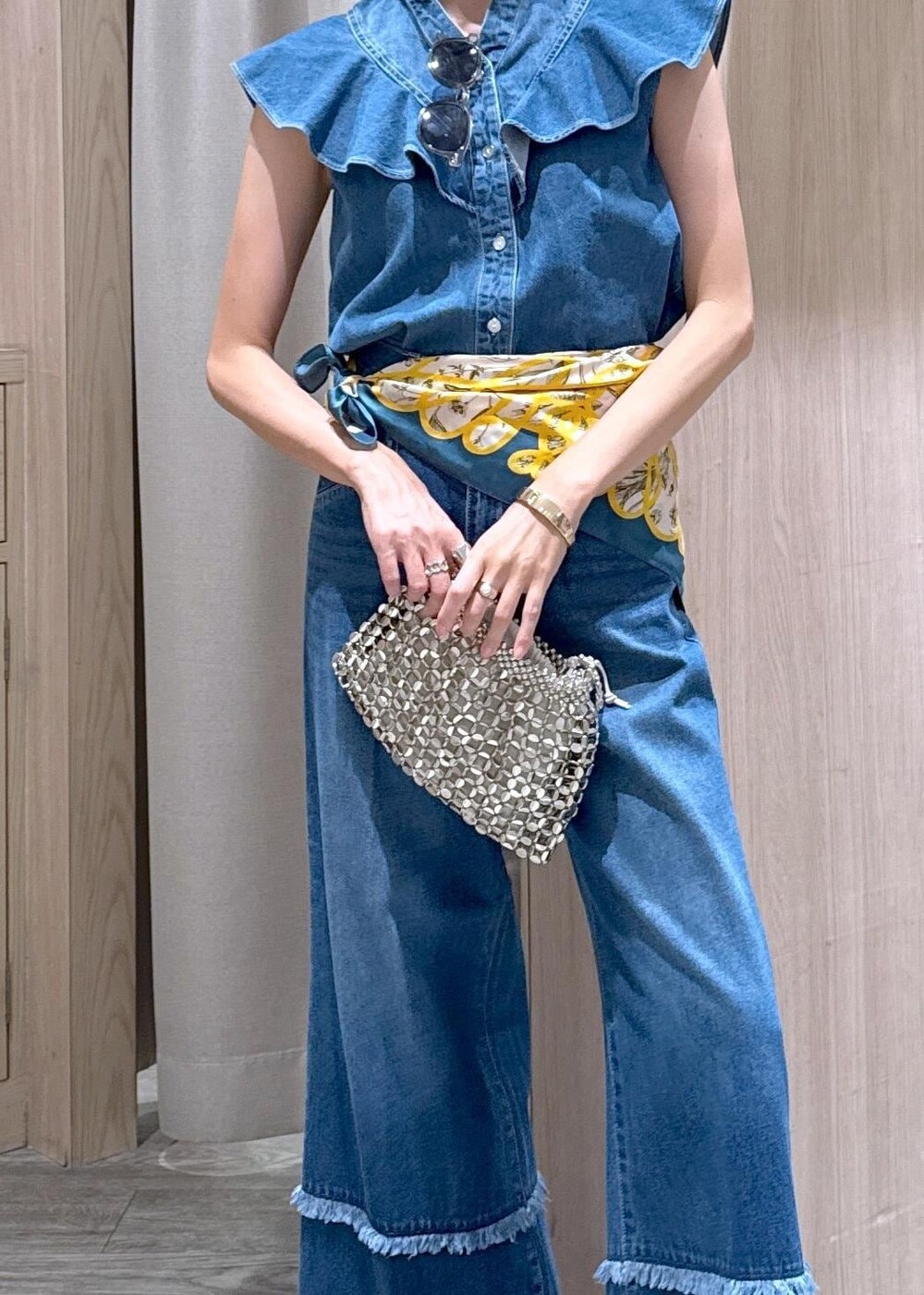シルバー系のハンドバッグ、ブルー系のシャツ/ブラウス、ブルー系のデニムパンツを着用したレディースの夏コーディネートの6枚目の写真