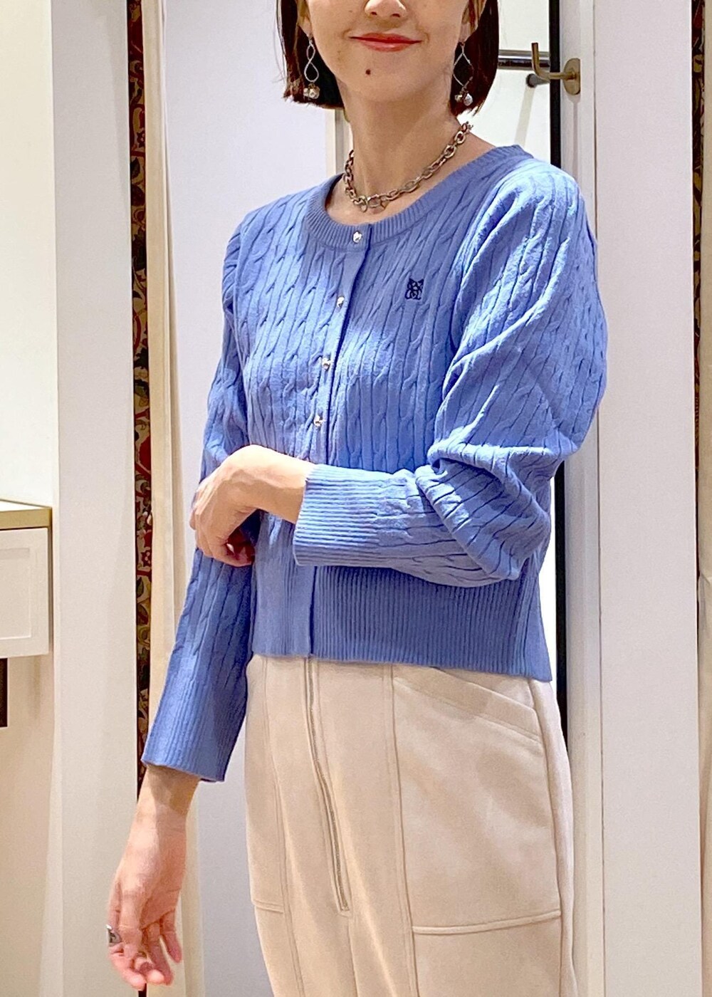 ホワイト系のショルダーバッグ、ブルー系のカーディガン/ボレロ、ベージュ系のスカートを着用したレディースの冬コーディネートの7枚目の写真