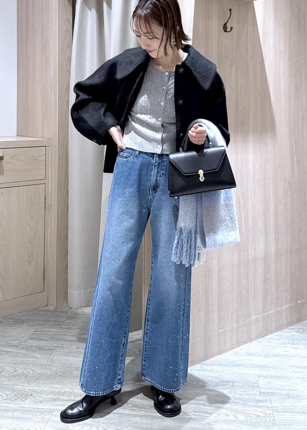 グレー系のカーディガン/ボレロ、ブラック系のブルゾン、ブルー系のデニムパンツを着用したレディースの秋コーディネートの2枚目の写真