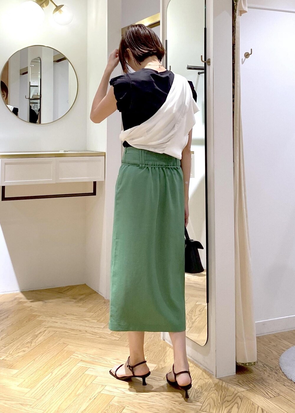 ブラック系のショルダーバッグ、ブラック系のサンダル、ホワイト系のカーディガン/ボレロを着用したレディースの夏コーディネートの2枚目の写真