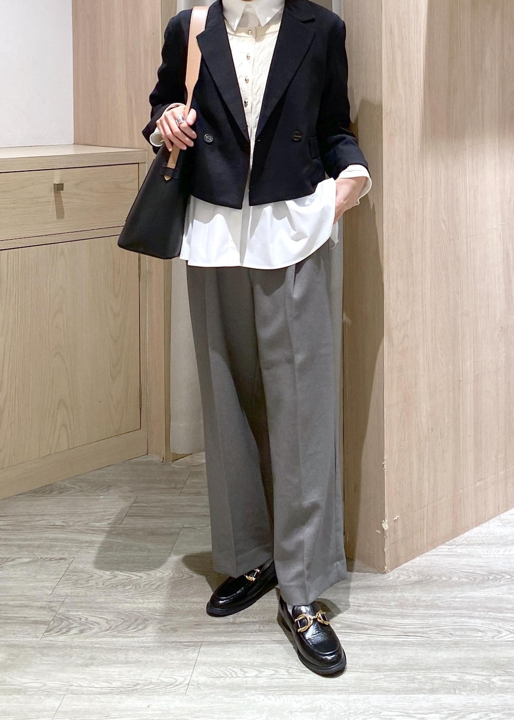 ブラック系のショルダーバッグ、グレー系のスラックス、ホワイト系のカーディガン/ボレロを着用したレディースの冬コーディネートの5枚目の写真