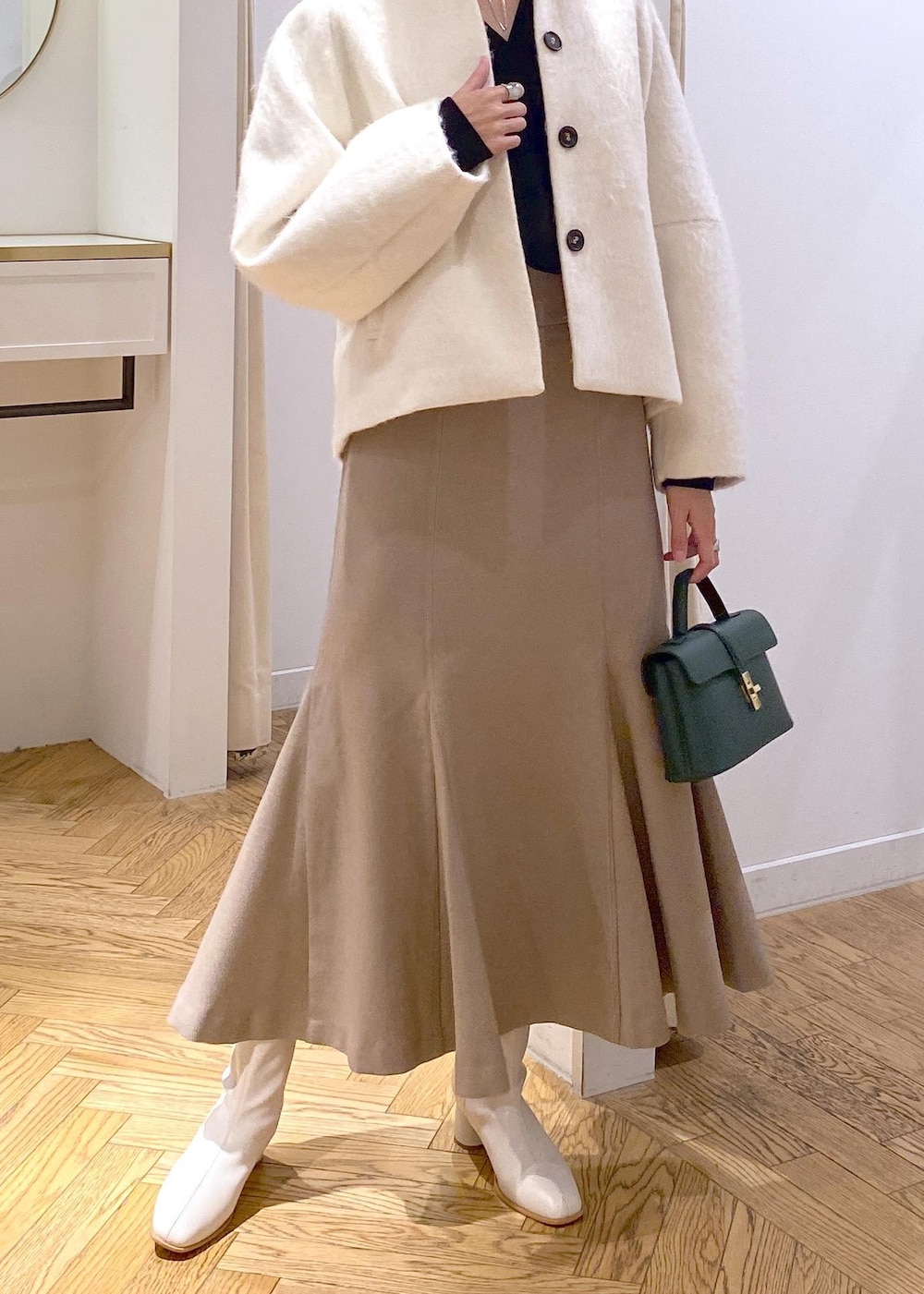 ホワイト系のブーツ、ベージュ系のスカート、ホワイト系のその他アウターを着用したレディースの秋コーディネートの3枚目の写真