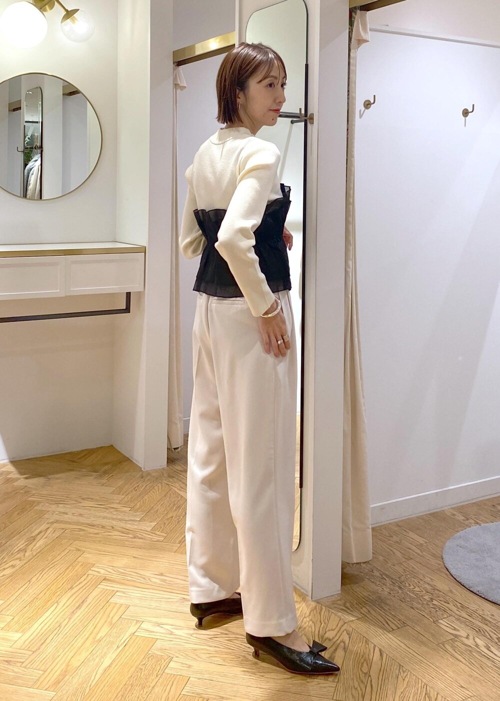 ブラック系のパンプス、ホワイト系のニット/セーター、ホワイト系のスラックスを着用したレディースの冬コーディネートの7枚目の写真