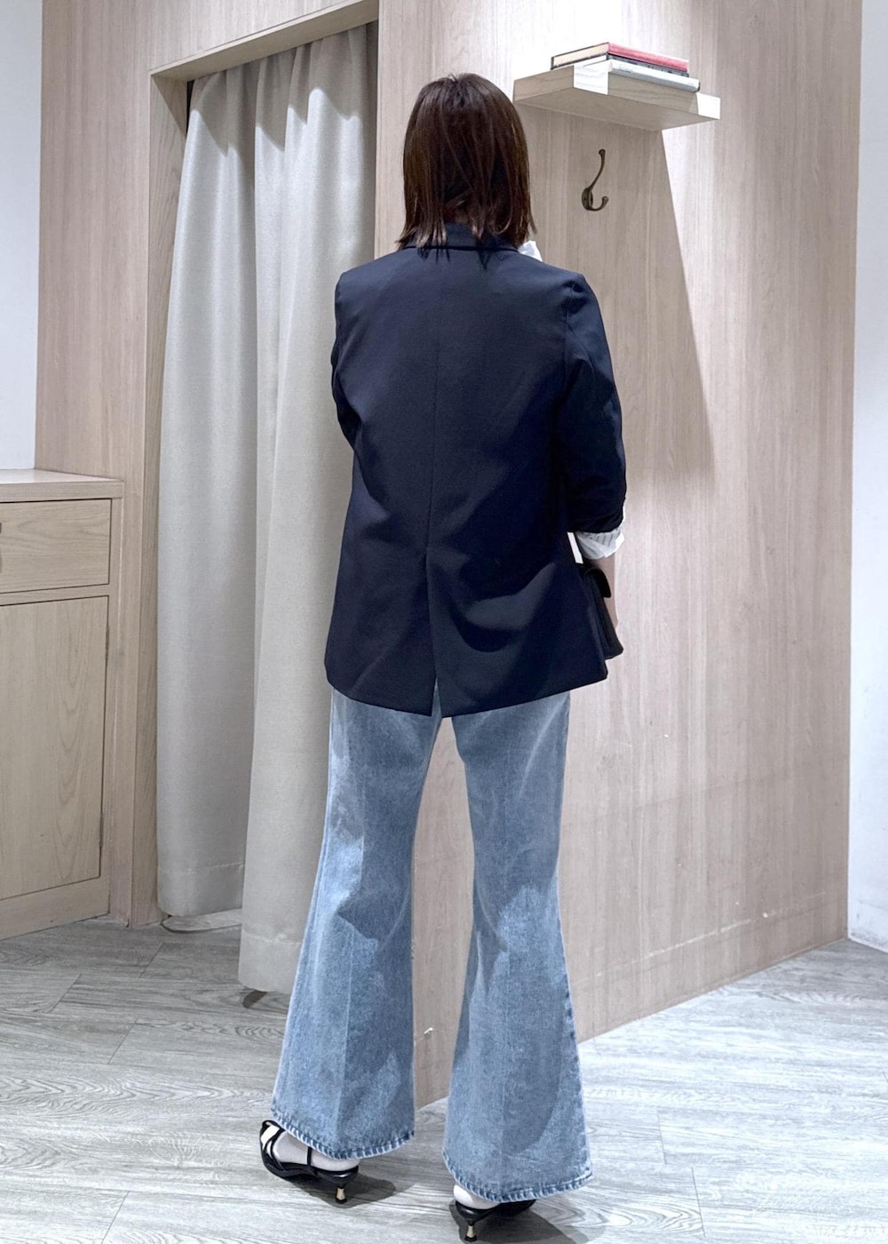 ブルー系のテーラードジャケット、ブラック系のショルダーバッグ、ブルー系のデニムパンツを着用したレディースの冬コーディネートの3枚目の写真