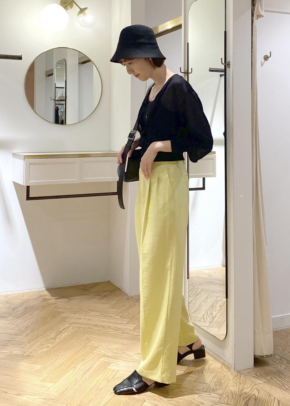ブラック系のキャミソール、イエロー系のスラックス、ブラック系のショルダーバッグを着用したレディースの夏コーディネートの2枚目の写真