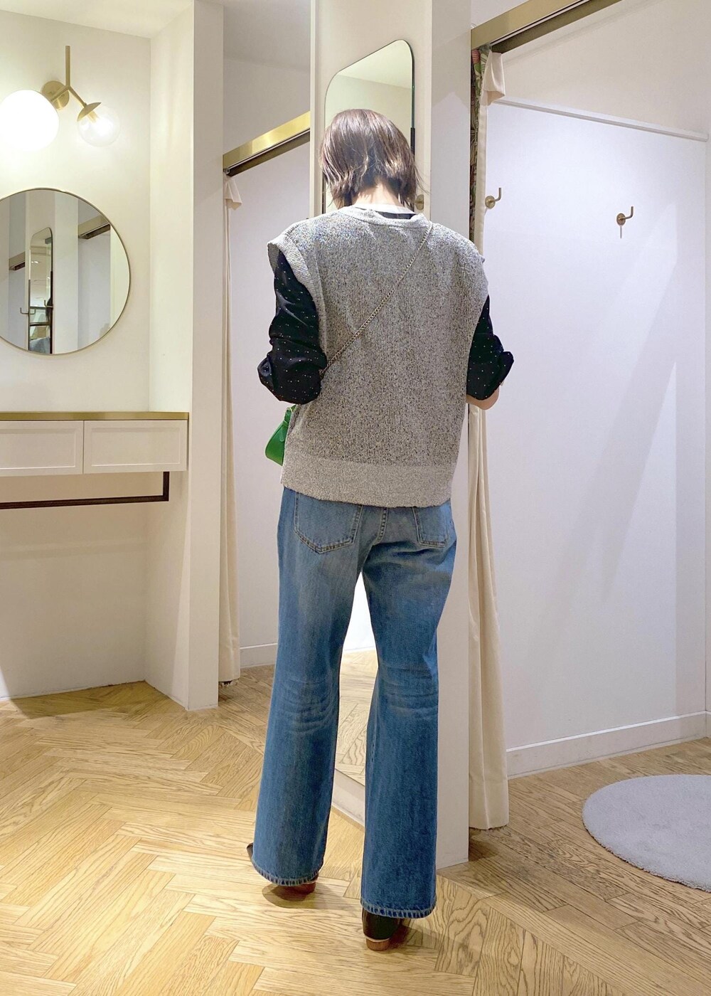 ブラック系のパンプス、ブルー系のデニムパンツ、ブラック系のベストを着用したレディースの春コーディネートの2枚目の写真