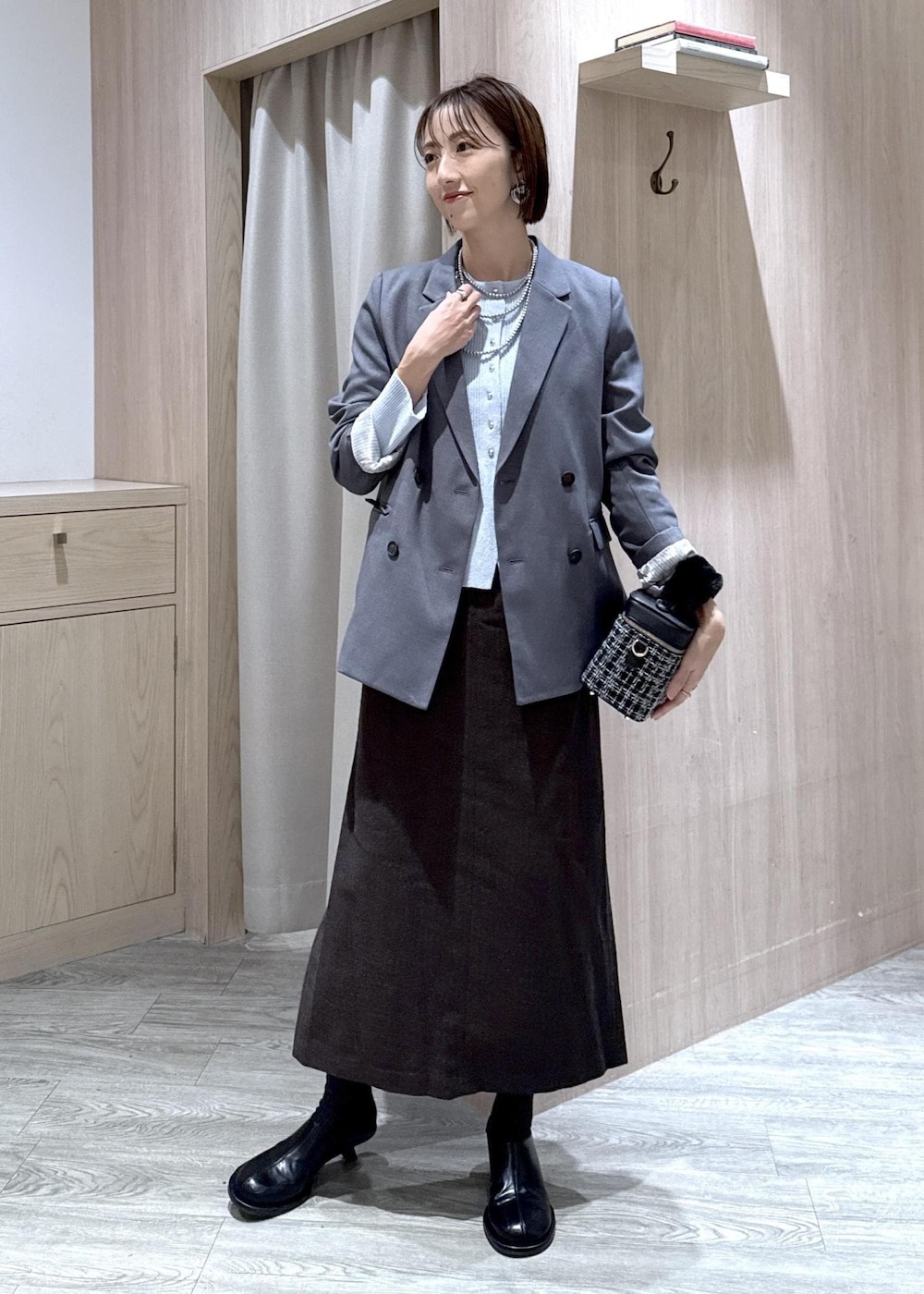 グレー系のテーラードジャケット、ブルー系のカーディガン/ボレロ、ブラウン系のスカートを着用したレディースの秋コーディネートの9枚目の写真