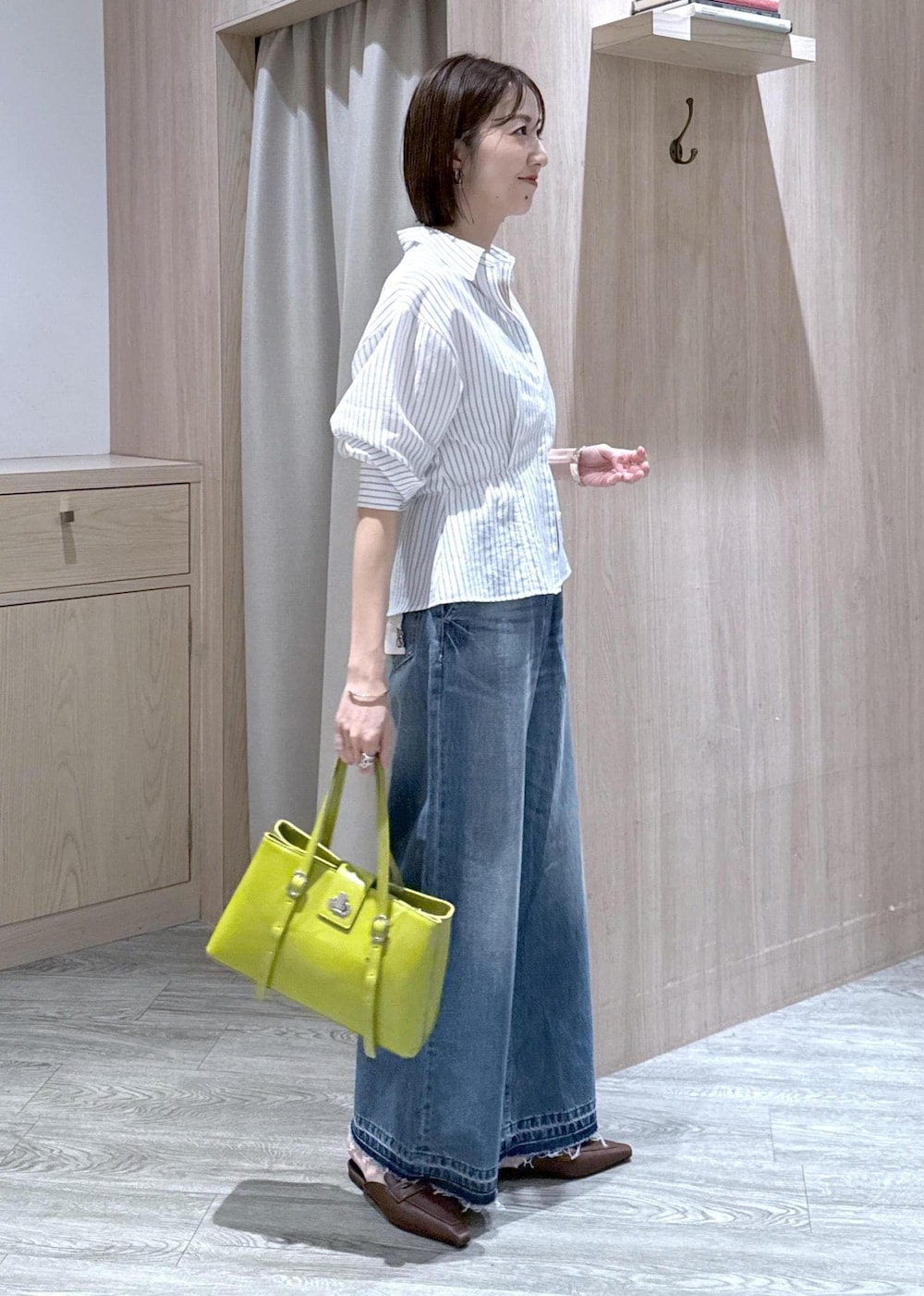 ブルー系のデニムパンツ、グリーン系のトートバッグ、ホワイト系のシャツ/ブラウスを着用したレディースの春コーディネートの3枚目の写真