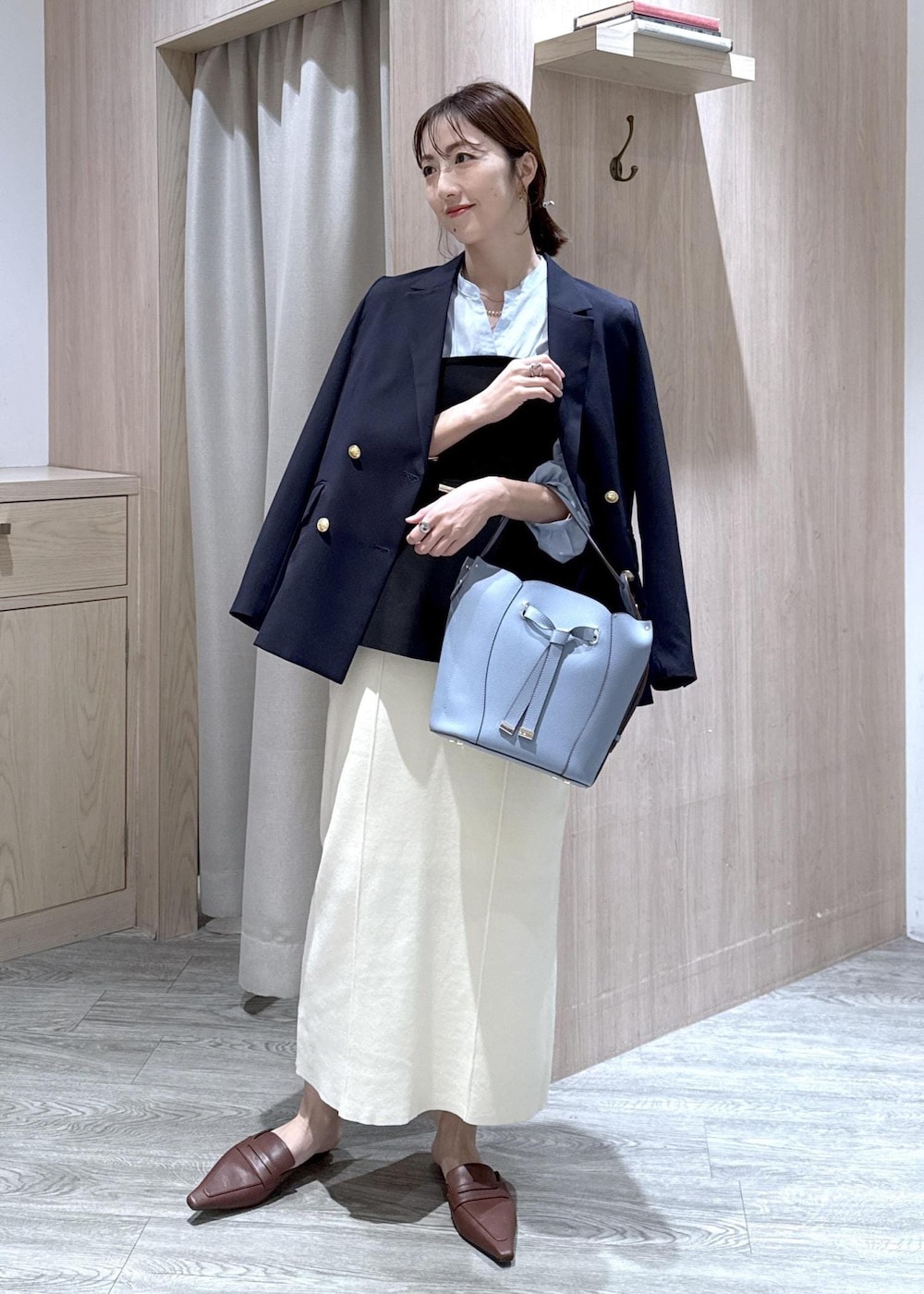 ブルー系のテーラードジャケット、ホワイト系のスカート、ブルー系のショルダーバッグを着用したレディースの春コーディネートの2枚目の写真