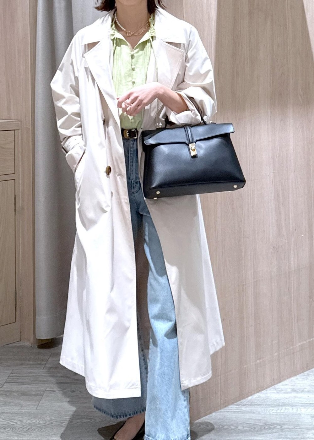 ブラック系のハンドバッグ、ブラック系のバレエシューズ、ホワイト系のトレンチコートを着用したレディースの春コーディネートの6枚目の写真