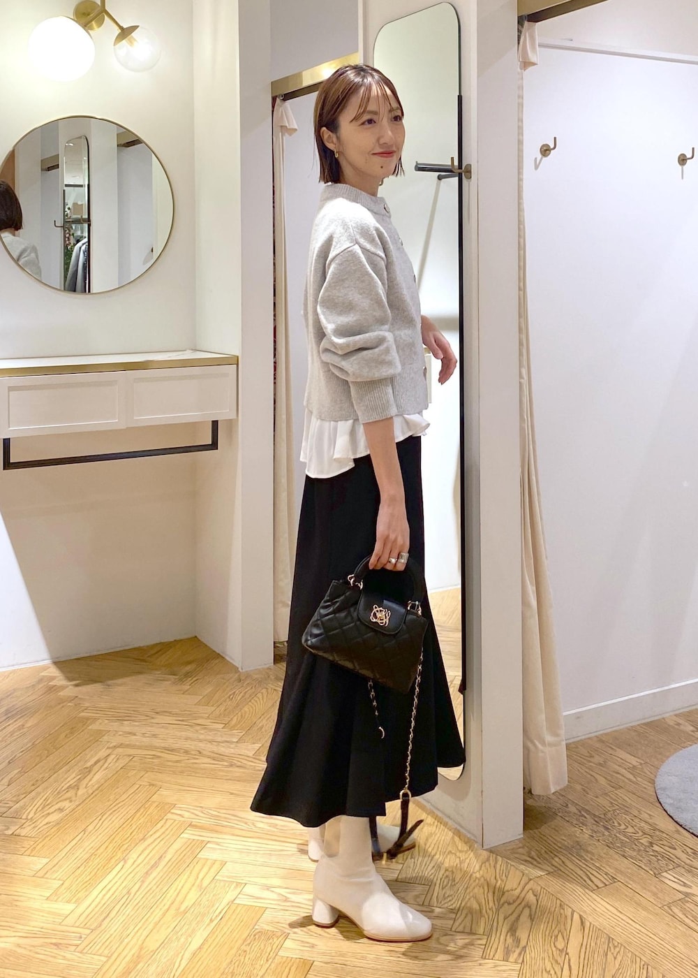 ホワイト系のシャツ/ブラウス、グレー系のカーディガン/ボレロ、ホワイト系のブーツを着用したレディースの冬コーディネートの5枚目の写真
