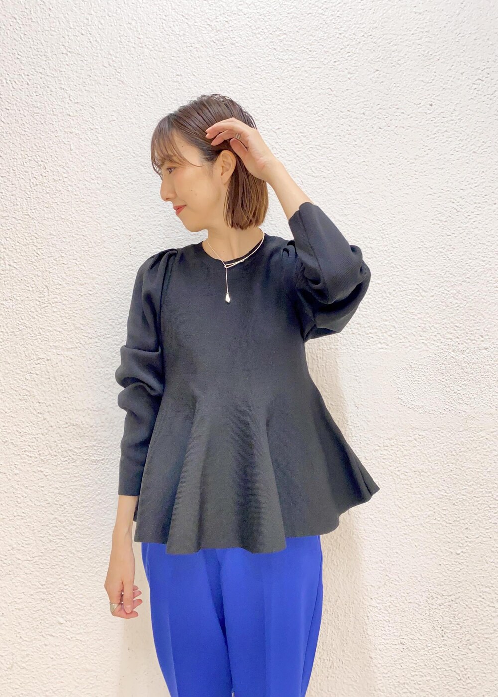 ブラック系のニット/セーター、ブルー系のスラックス、ゴールド系のチョーカーを着用したレディースの冬コーディネートの3枚目の写真