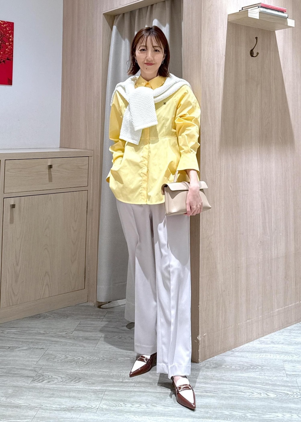 ベージュ系のショルダーバッグ、ブラウン系のパンプス、イエロー系のシャツ/ブラウスを着用したレディースの春コーディネートの3枚目の写真