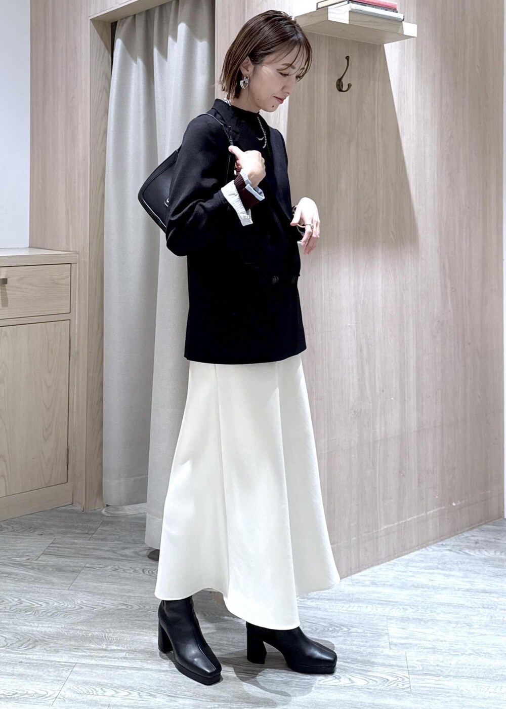 ブラック系のショルダーバッグ、ブラック系のテーラードジャケット、ブラック系のブーツを着用したレディースの冬コーディネートの2枚目の写真