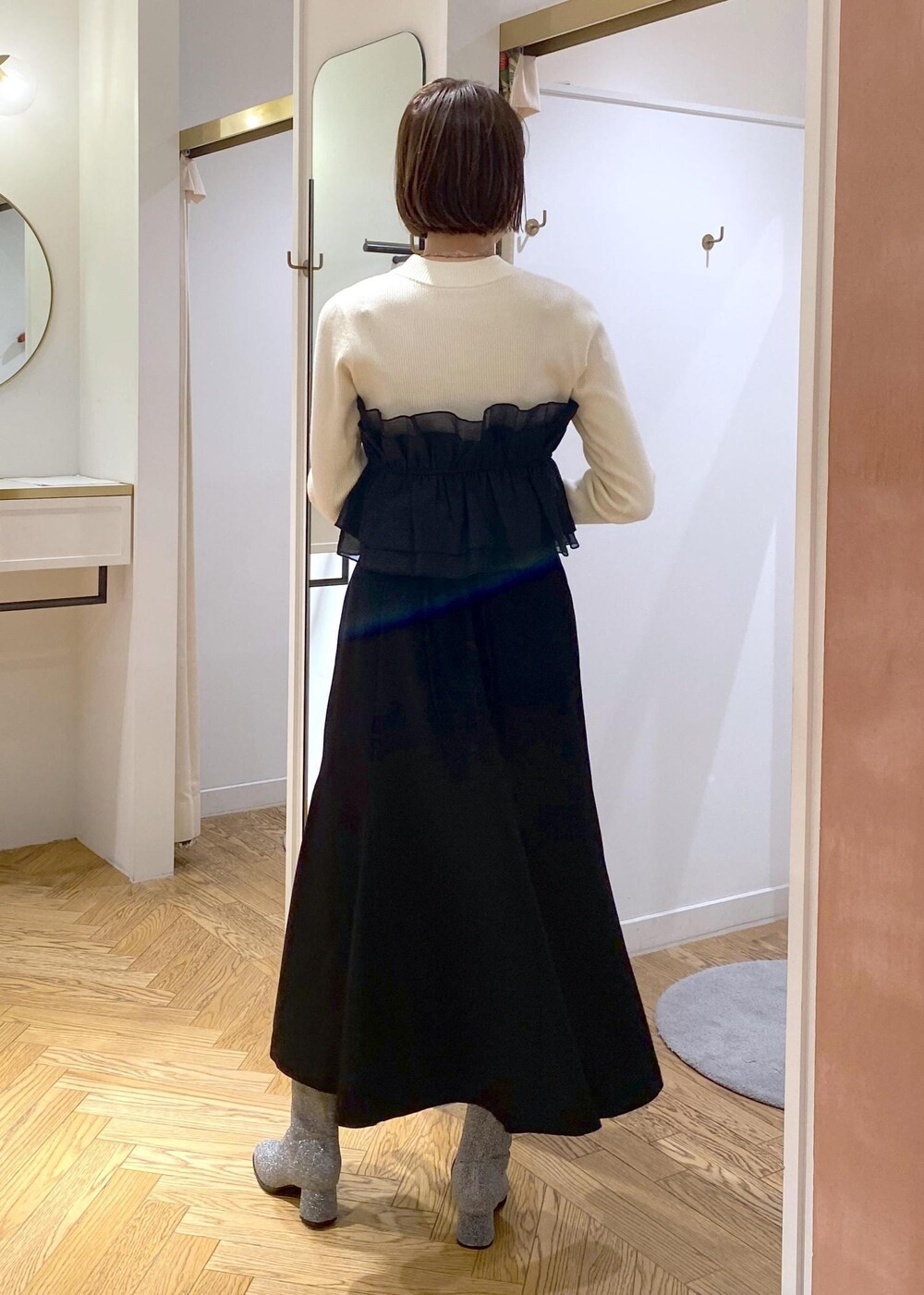 シルバー系のブーツ、ブラック系のスカート、ホワイト系のニット/セーターを着用したレディースの冬コーディネートの4枚目の写真