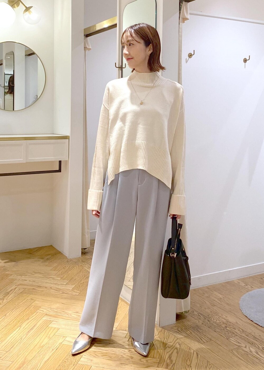 シルバー系のパンプス、ブラック系のショルダーバッグ、ブルー系のスラックスを着用したレディースの秋コーディネートの8枚目の写真