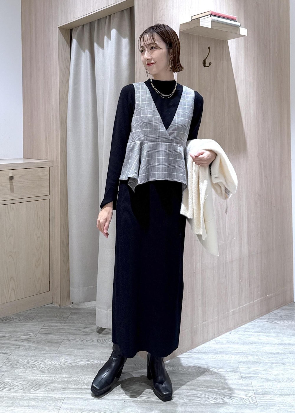 ブルー系のハンドバッグ、ホワイト系のノーカラージャケット、ブラック系のブーツを着用したレディースの秋コーディネートの3枚目の写真