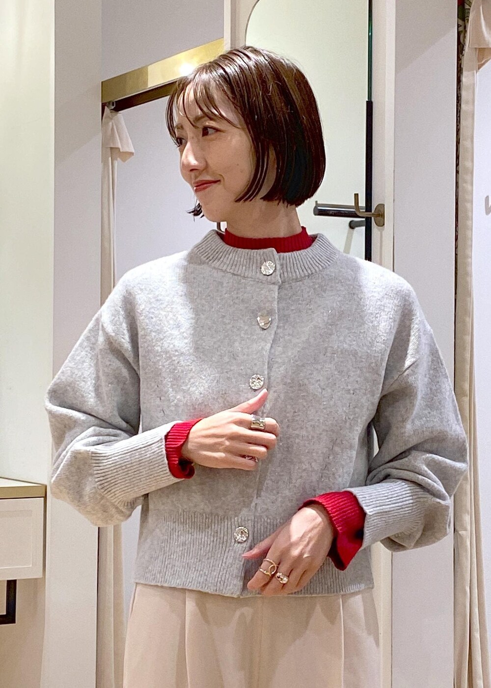 ホワイト系のブーツ、グレー系のカーディガン/ボレロ、レッド系のニット/セーターを着用したレディースの冬コーディネートの8枚目の写真