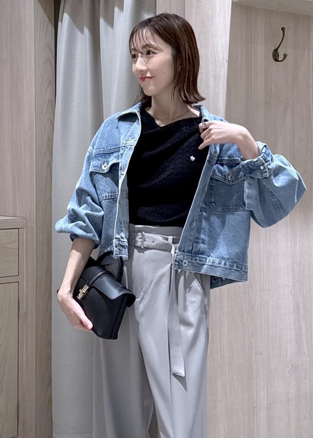 ブラック系のショルダーバッグ、ブルー系のデニムジャケット、グレー系のスラックスを着用したレディースの春コーディネートの5枚目の写真