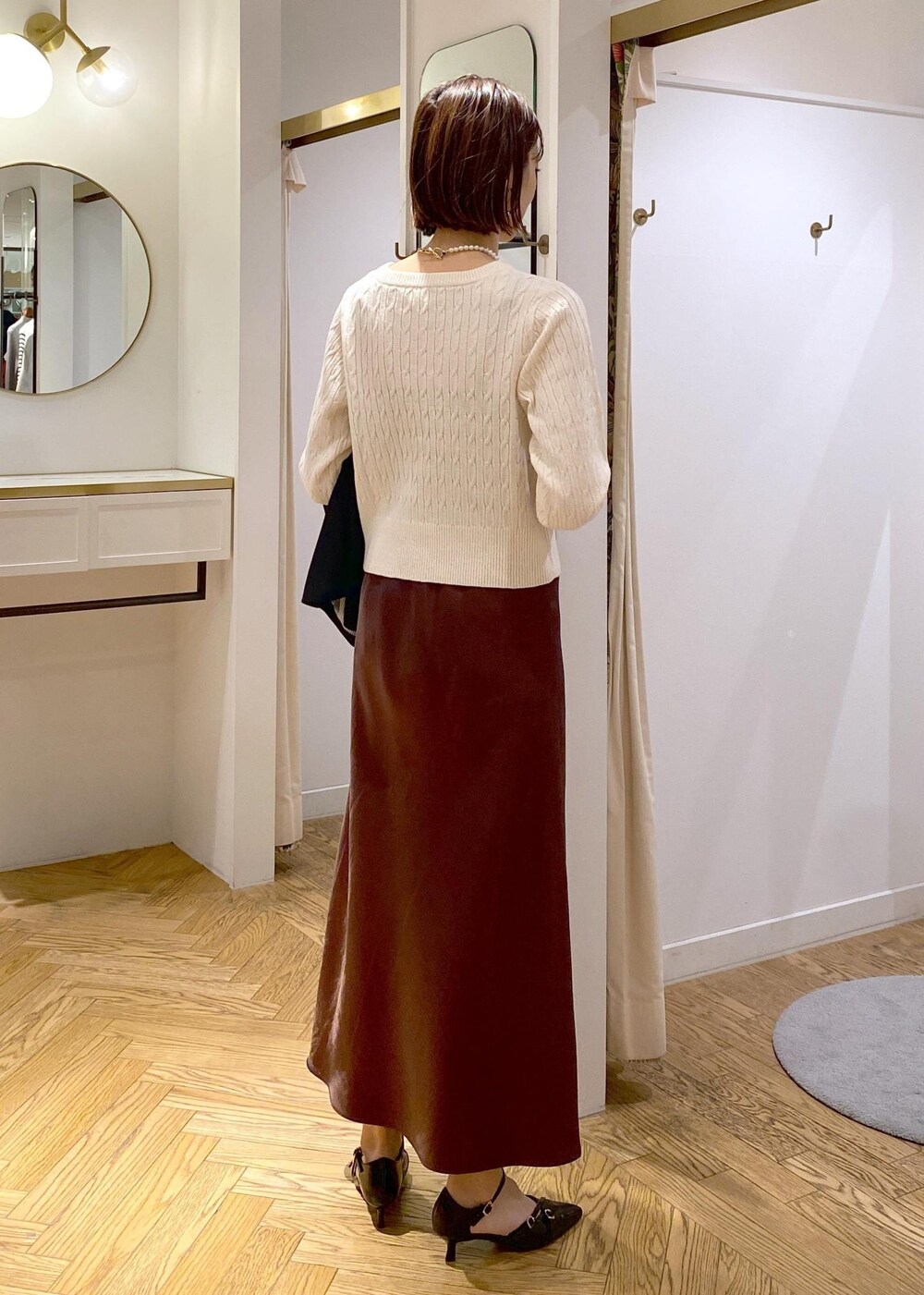 ブラック系のテーラードジャケット、ブラック系のパンプス、ブラウン系のスカートを着用したレディースの冬コーディネートの8枚目の写真