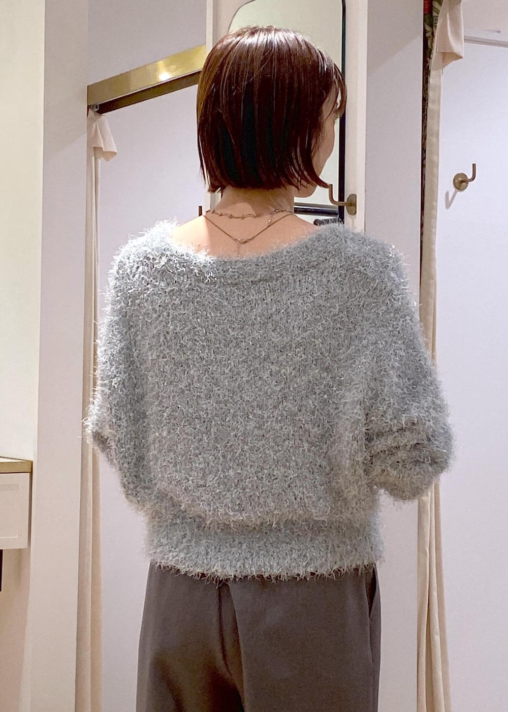 グレー系のスラックス、ブルー系のショルダーバッグ、ブラック系のパンプスを着用したレディースの冬コーディネートの10枚目の写真