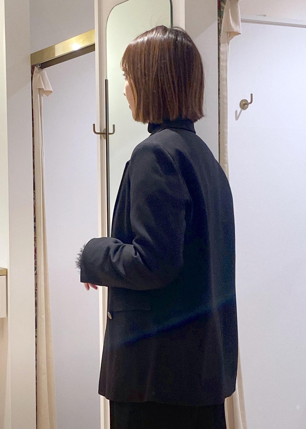 ブラック系のニット/セーター、ブラック系のスラックス、ブラック系のテーラードジャケットを着用したレディースの冬コーディネートの10枚目の写真