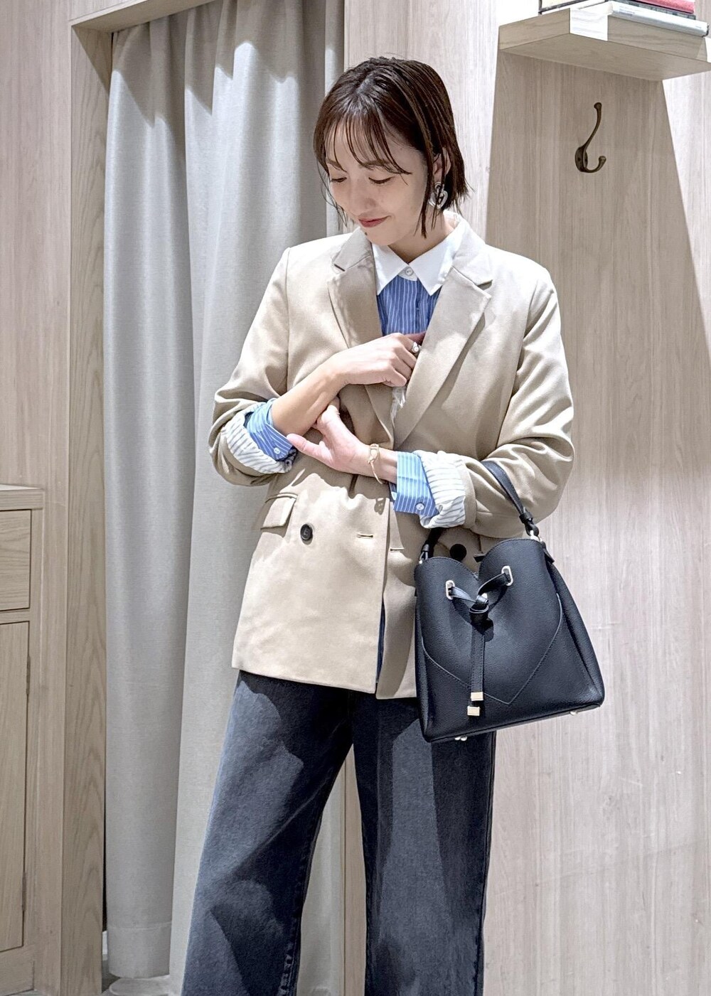 ブラック系のショルダーバッグ、ベージュ系のテーラードジャケット、ブラック系のブーツを着用したレディースの秋コーディネートの4枚目の写真