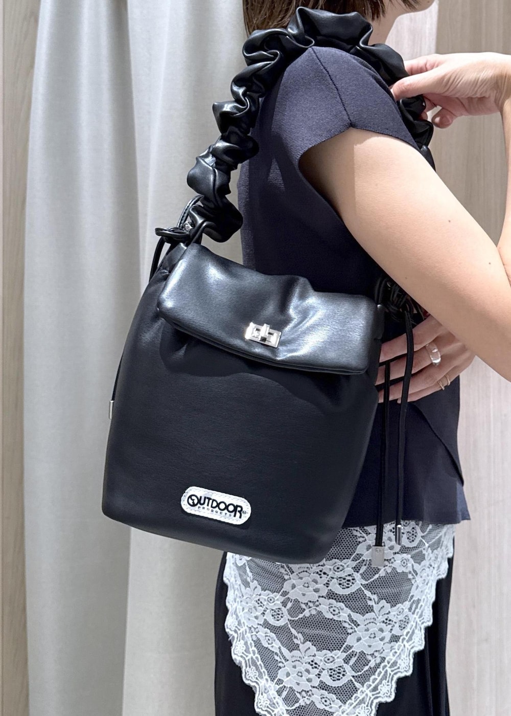 ブラック系のショルダーバッグ、ブラック系のパンプス、グレー系のニット/セーターを着用したレディースの夏コーディネートの5枚目の写真