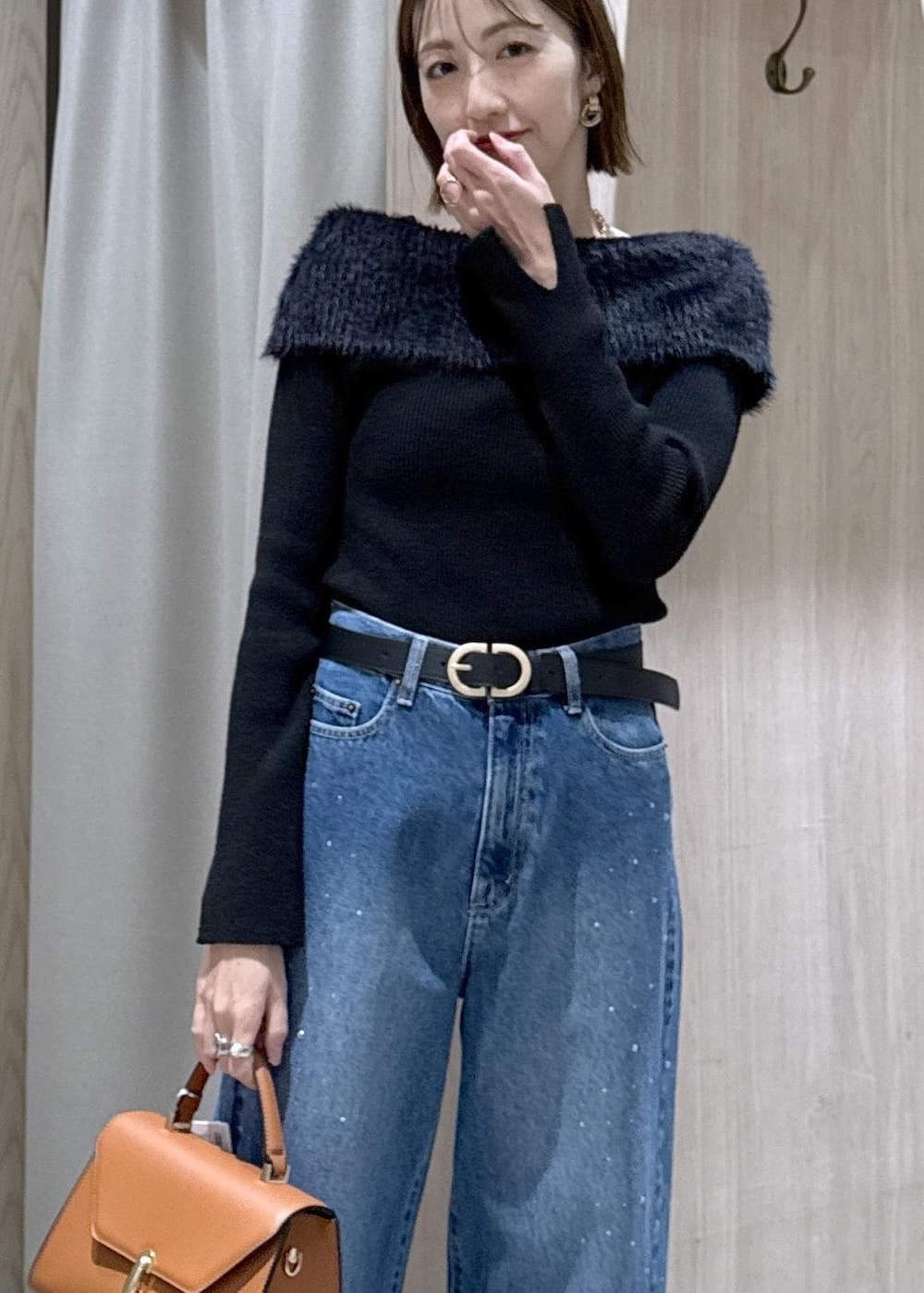 ブルー系のデニムパンツ、イエロー系のハンドバッグ、ブラック系のニット/セーターを着用したレディースの冬コーディネートの5枚目の写真