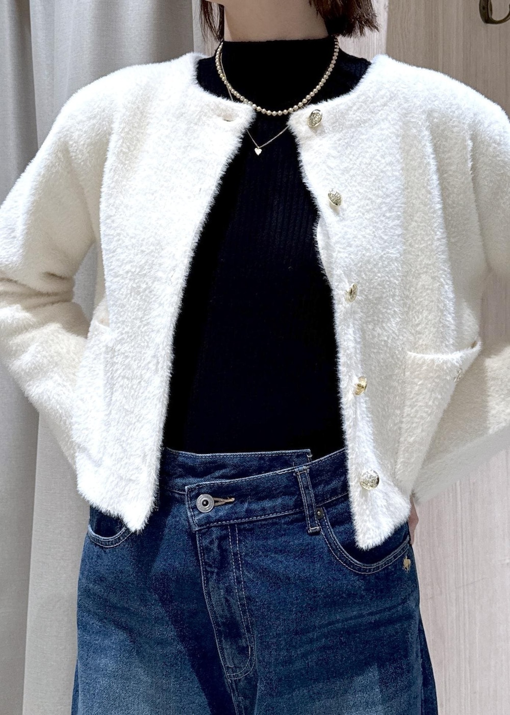 ホワイト系のショルダーバッグ、ブルー系のデニムパンツ、ブラック系のニット/セーターを着用したレディースの冬コーディネートの6枚目の写真