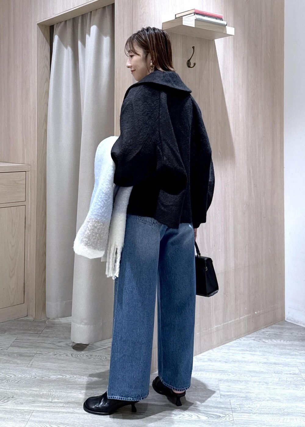 グレー系のカーディガン/ボレロ、ブラック系のブルゾン、ブルー系のデニムパンツを着用したレディースの秋コーディネートの4枚目の写真